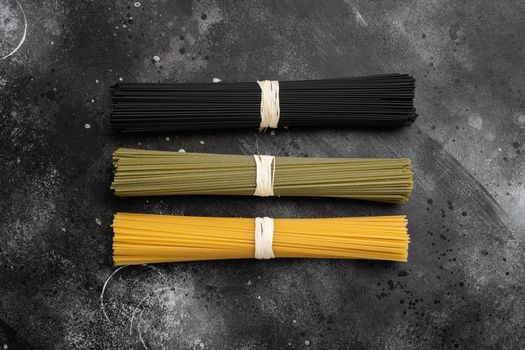 Colored spaghetti raw dry set, on black dark stone table background, top view flat lay