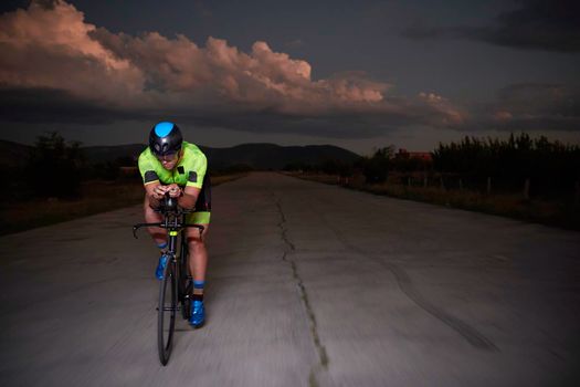 triathlon athlete cycling fast riding professional racing bike at night