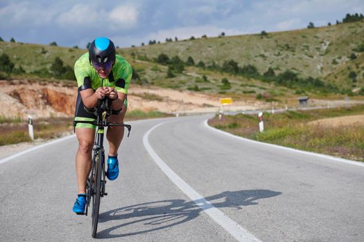 triathlon athlete riding professional racing bike at workout on curvy country road