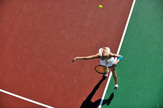 young fit woman play tennis outdoor on orange tennis field at early morning