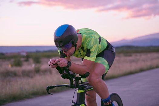 triathlon athlete riding professional racing bike on morning workout sunset or sunrise in background