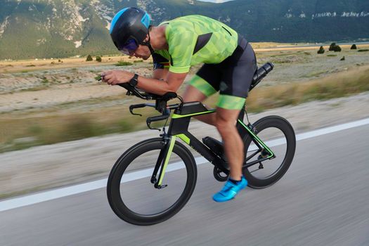 triathlon athlete riding professional racing bike at workout on curvy country road
