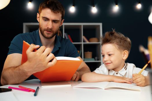 Father helping his little son with school homework close up