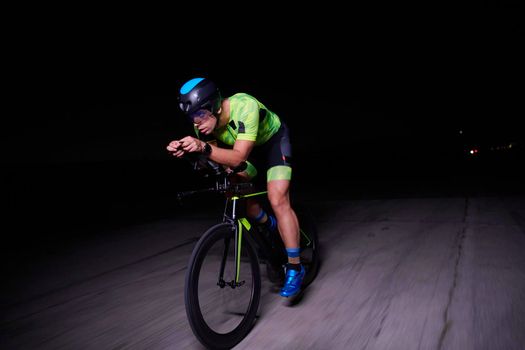 triathlon athlete cycling fast riding professional racing bike at night