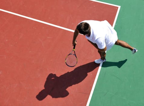 young man play tennis outdoor on orange tennis court at early morning