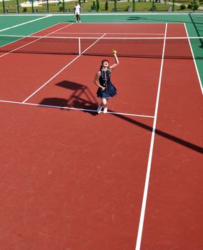 young fit woman play tennis outdoor on orange tennis field at early morning