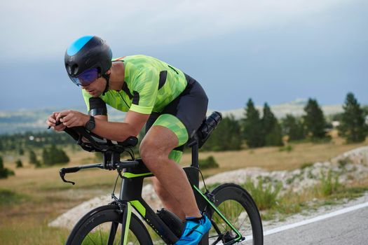 triathlon athlete riding professional racing bike at workout on curvy country road