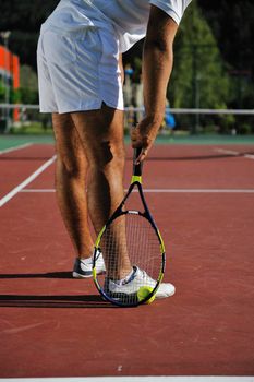 young man play tennis outdoor on orange tennis field at early morning