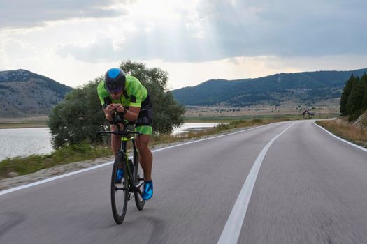 triathlon athlete riding professional racing bike at workout on curvy country road