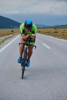 triathlon athlete riding professional racing bike at workout on curvy country road