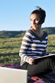 young teen girl read book and study homework outdoor in nature with blue sky in background