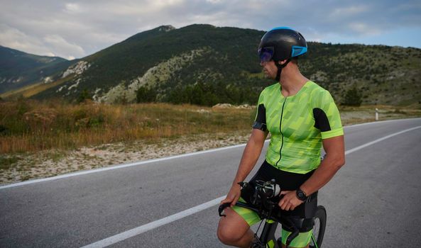 triathlon athlete riding professional racing bike at workout on curvy country road