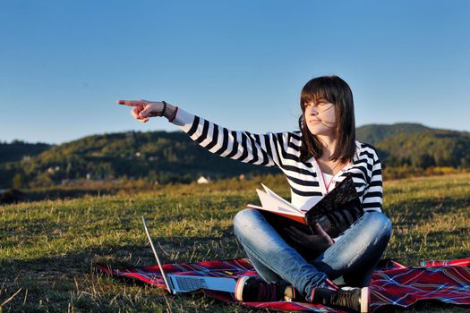 young teen girl read book and study homework outdoor in nature with blue sky in background