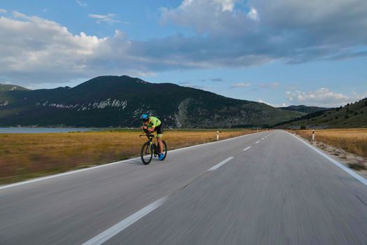 triathlon athlete riding professional racing bike at workout on curvy country road