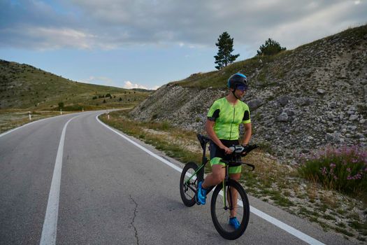 triathlon athlete riding professional racing bike at workout on curvy country road