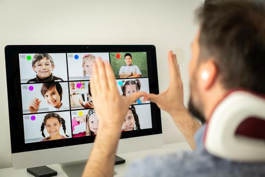 Male teacher having online conference with school children working at home