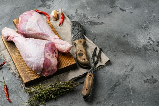 Fresh uncooked turkey legs set, on wooden cutting board, on gray stone table background, with copy space for text