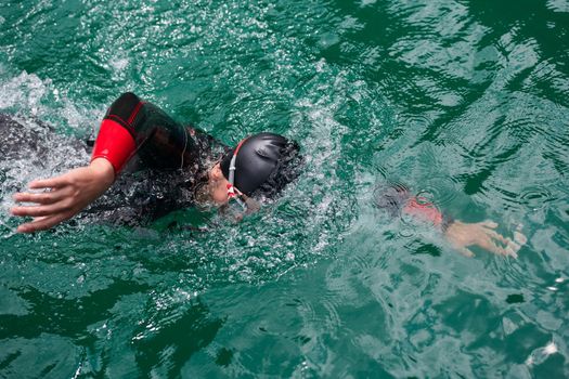 triathlon athlete swimming on extreme morning training in green lake wearing wetsuit