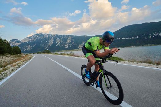 triathlon athlete riding professional racing bike at workout on curvy country road