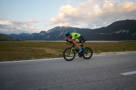 triathlon athlete riding professional racing bike at workout on curvy country road