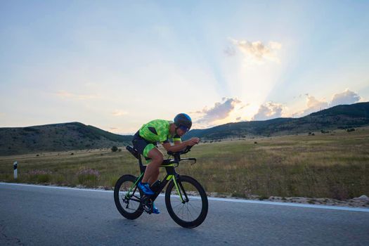 triathlon athlete riding professional racing bike at workout on curvy country road