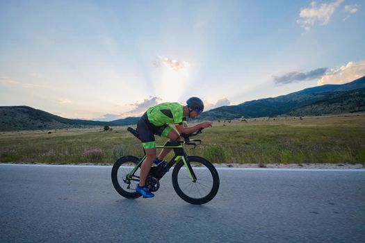 triathlon athlete riding professional racing bike at workout on curvy country road