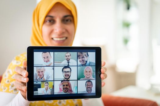 Muslim womah holding tablet with zoom conference screen