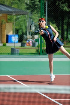 young fit woman play tennis outdoor on orange tennis field at early morning