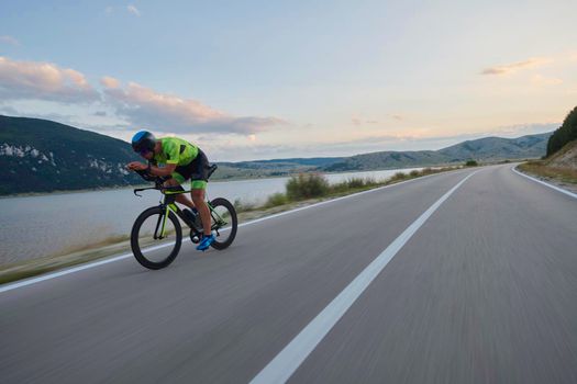 triathlon athlete riding professional racing bike at workout on curvy country road