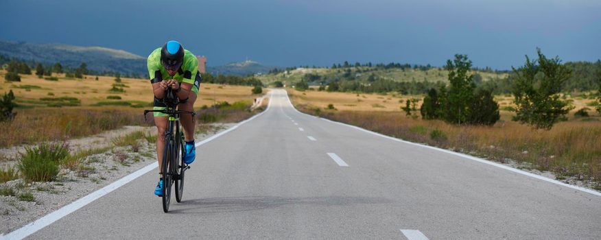 triathlon athlete riding professional racing bike at workout on curvy country road