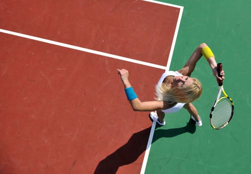 young fit woman play tennis outdoor on orange tennis field at early morning