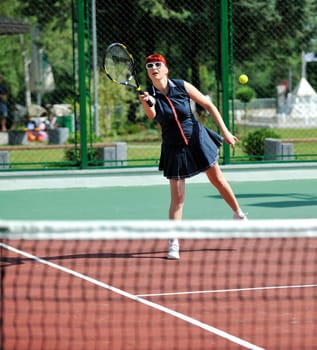 young fit woman play tennis outdoor on orange tennis field at early morning