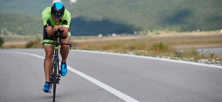 triathlon athlete riding professional racing bike at workout on curvy country road