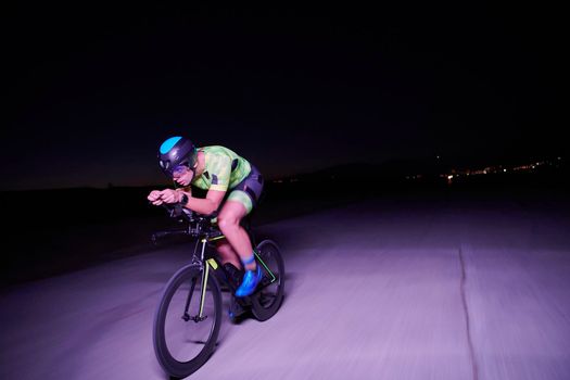 triathlon athlete cycling fast riding professional racing bike at night