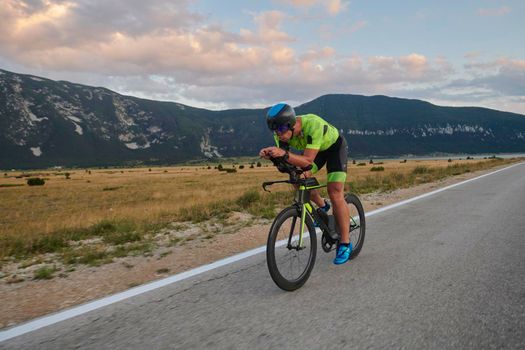 triathlon athlete riding professional racing bike at workout on curvy country road