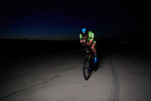 triathlon athlete cycling fast riding professional racing bike at night