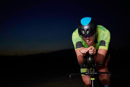 triathlon athlete cycling fast riding professional racing bike at night