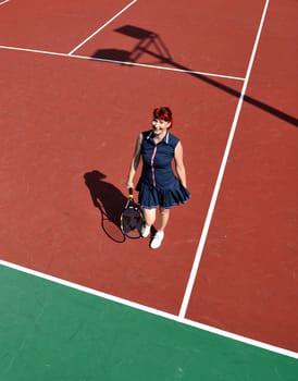 young fit woman play tennis outdoor on orange tennis field at early morning