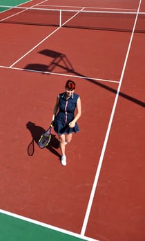 young fit woman play tennis outdoor on orange tennis field at early morning