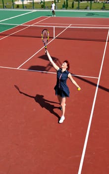 young fit woman play tennis outdoor on orange tennis field at early morning