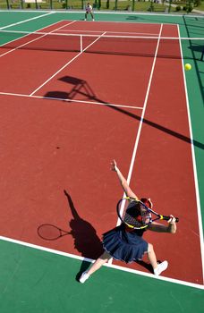 young fit woman play tennis outdoor on orange tennis field at early morning