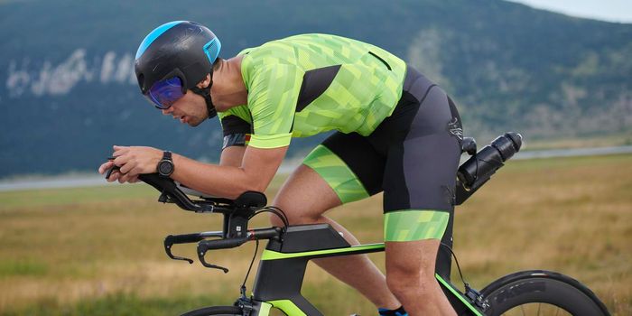 triathlon athlete riding professional racing bike at workout on curvy country road