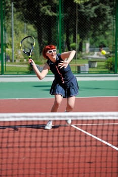 young fit woman play tennis outdoor on orange tennis field at early morning