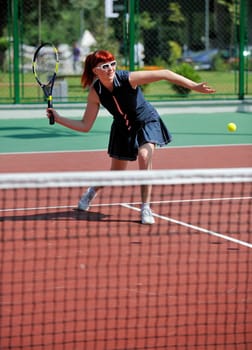 young fit woman play tennis outdoor on orange tennis field at early morning