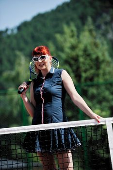 young fit woman play tennis outdoor on orange tennis field at early morning