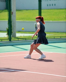 young fit woman play tennis outdoor on orange tennis field at early morning