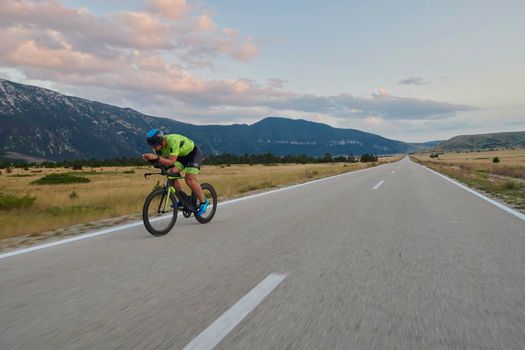 triathlon athlete riding professional racing bike at workout on curvy country road