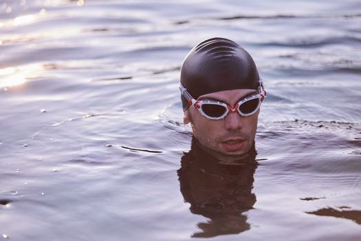 real triathlete swimmer having a break during hard training at lake on beautiful morning