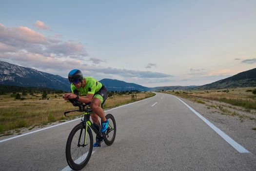 triathlon athlete riding professional racing bike at workout on curvy country road