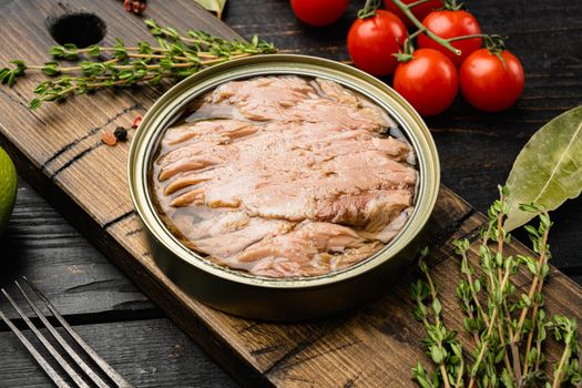 Open tuna tin set, on black wooden table background